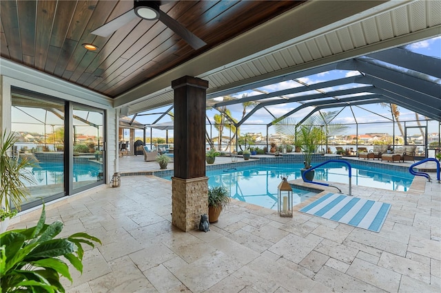 outdoor pool featuring glass enclosure, a patio area, and ceiling fan