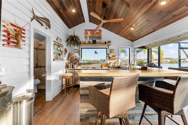 bar featuring wooden walls, wood finished floors, lofted ceiling, wooden ceiling, and indoor bar