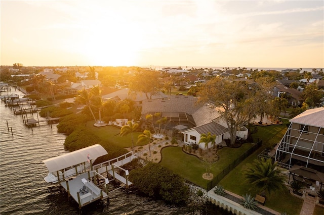 aerial view at dusk with a water view and a residential view