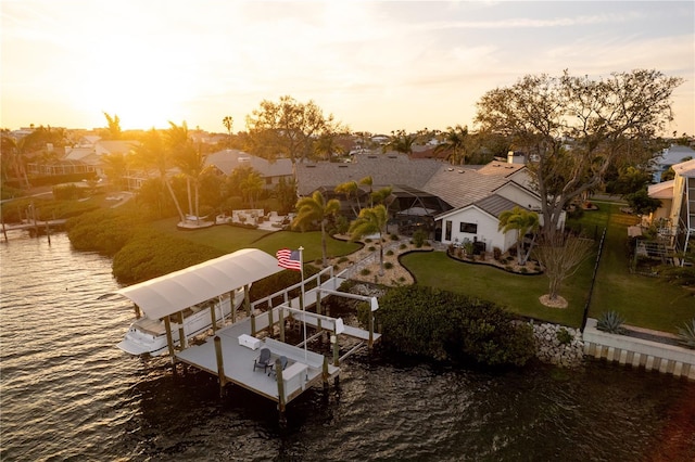 view of dock with a lawn, a water view, a residential view, and boat lift