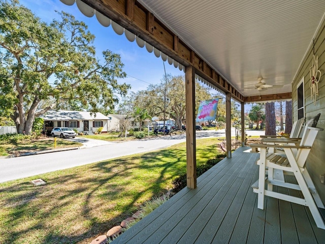 wooden deck featuring ceiling fan, a porch, a lawn, and a residential view