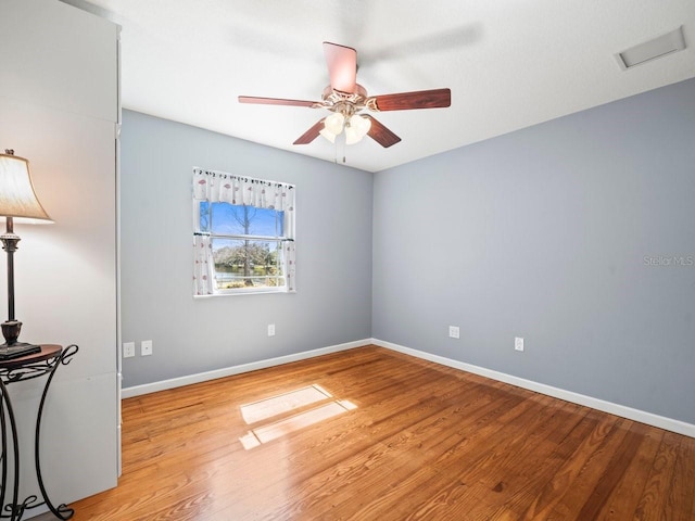 empty room with light wood finished floors, ceiling fan, visible vents, and baseboards