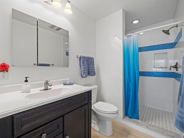 full bath featuring a stall shower, vanity, toilet, and wood finished floors