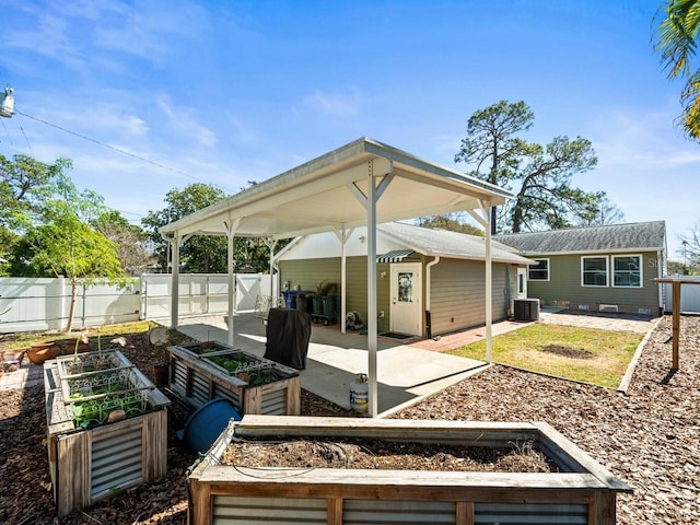 view of patio / terrace with an outbuilding, cooling unit, a vegetable garden, and fence