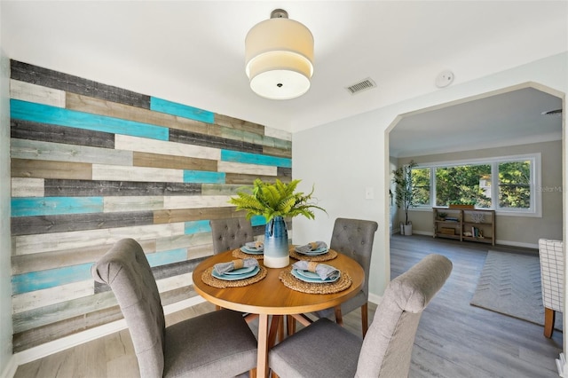 dining area with wooden walls and hardwood / wood-style floors