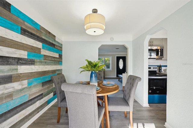 dining room with dark wood-type flooring and wooden walls