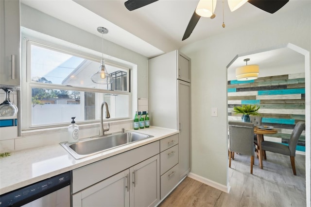 kitchen with light hardwood / wood-style flooring, hanging light fixtures, gray cabinetry, dishwasher, and sink