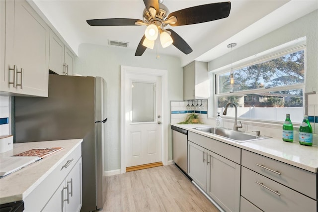 kitchen featuring stainless steel appliances, light hardwood / wood-style flooring, sink, gray cabinets, and decorative backsplash