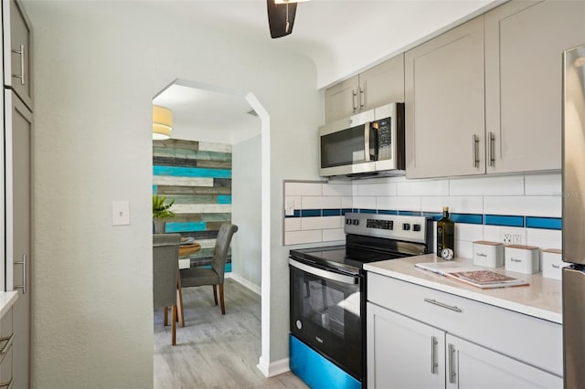 kitchen featuring appliances with stainless steel finishes, decorative backsplash, gray cabinets, and light hardwood / wood-style flooring