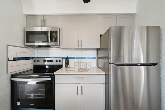 kitchen with appliances with stainless steel finishes, gray cabinets, and backsplash