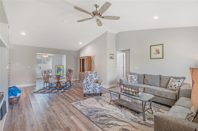 living room with baseboards, a ceiling fan, vaulted ceiling, and wood finished floors