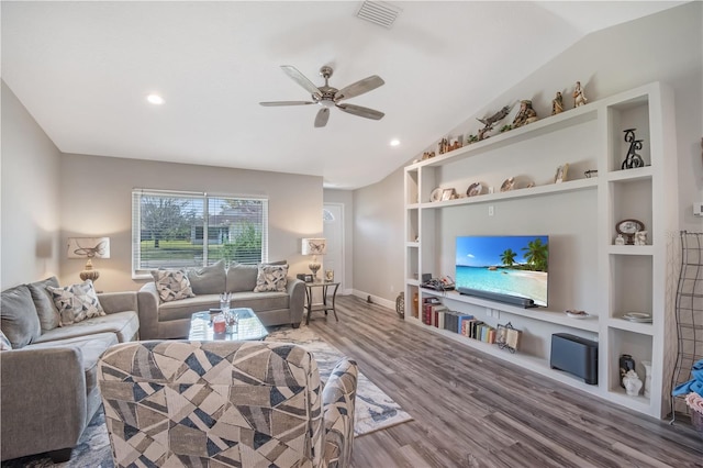 living area featuring built in features, lofted ceiling, visible vents, and wood finished floors