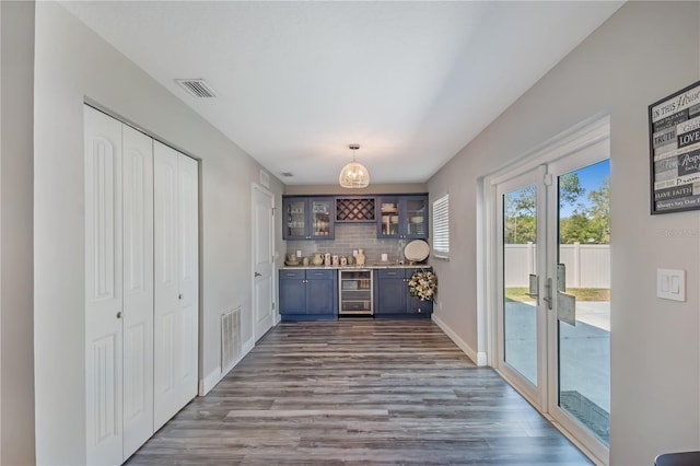 bar with dark wood-style floors, beverage cooler, visible vents, and backsplash