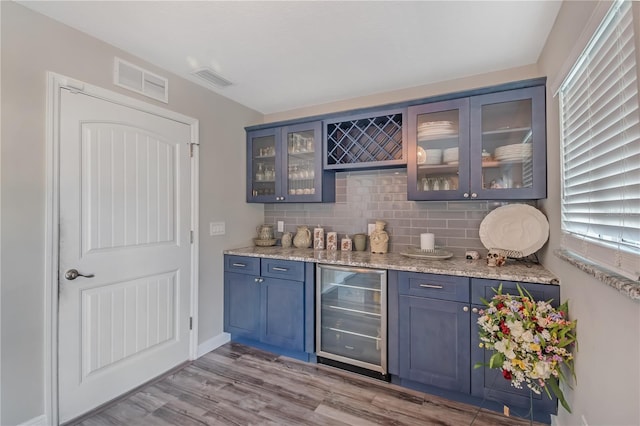 bar featuring beverage cooler, wood finished floors, visible vents, and decorative backsplash