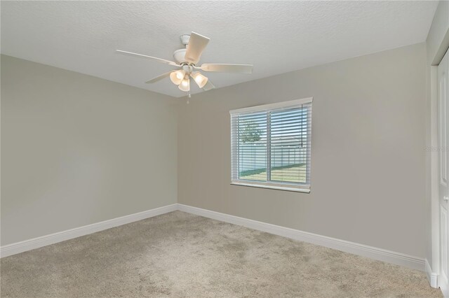 unfurnished room featuring light carpet, ceiling fan, a textured ceiling, and baseboards