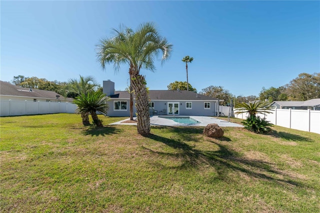 back of property featuring a fenced backyard, a yard, french doors, a fenced in pool, and a patio area