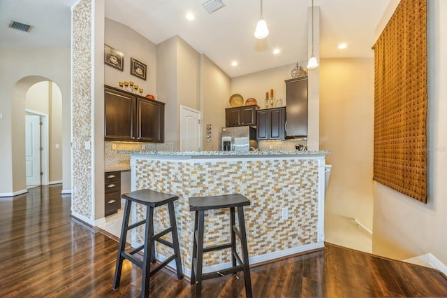 kitchen with visible vents, arched walkways, dark brown cabinets, and stainless steel refrigerator with ice dispenser