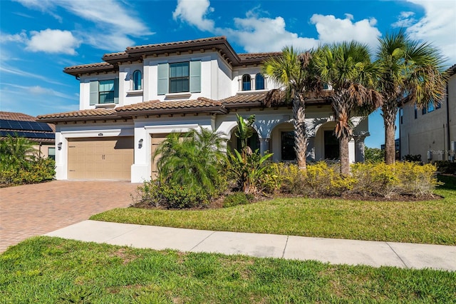 mediterranean / spanish-style house featuring a front lawn and a garage