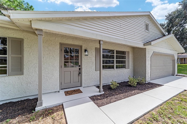 doorway to property featuring a garage and stucco siding