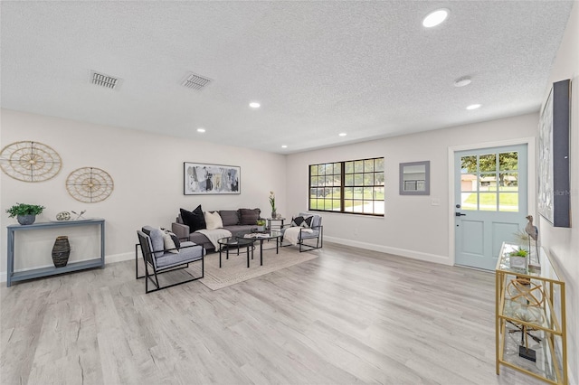 living area with recessed lighting, visible vents, a textured ceiling, wood finished floors, and baseboards