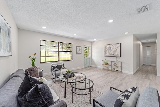 living area with light wood finished floors, baseboards, visible vents, and recessed lighting