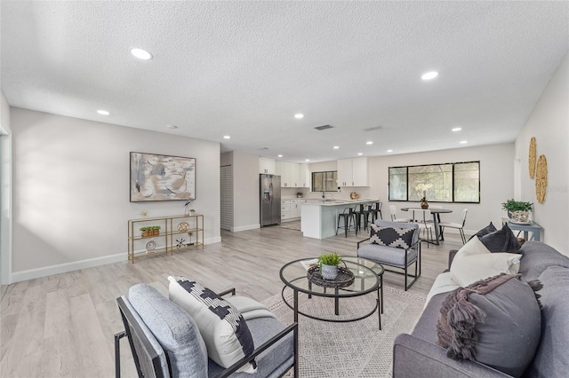 living area with recessed lighting, visible vents, and light wood finished floors