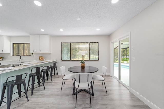 dining space featuring plenty of natural light, light wood-style flooring, and baseboards