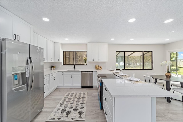 kitchen featuring light countertops, appliances with stainless steel finishes, a sink, and white cabinets