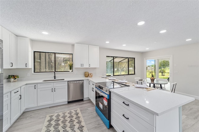 kitchen featuring appliances with stainless steel finishes, light countertops, a sink, and a peninsula