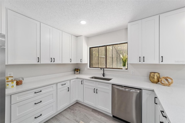 kitchen with light wood-type flooring, light countertops, a sink, and stainless steel dishwasher