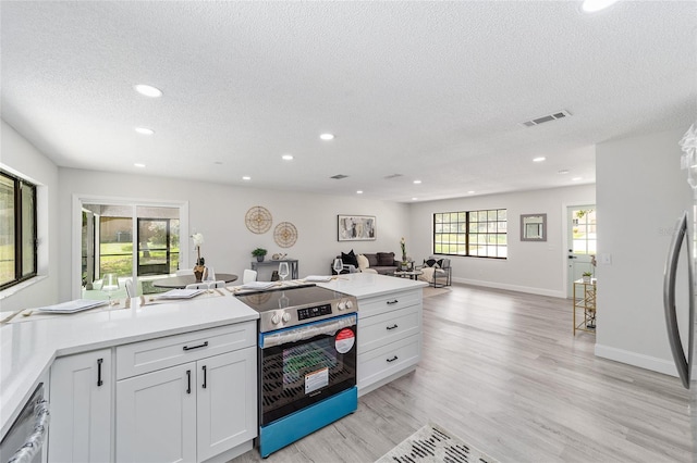 kitchen with dishwashing machine, visible vents, light wood-style floors, open floor plan, and stainless steel electric range oven