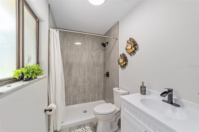 full bath with a stall shower, vanity, and toilet