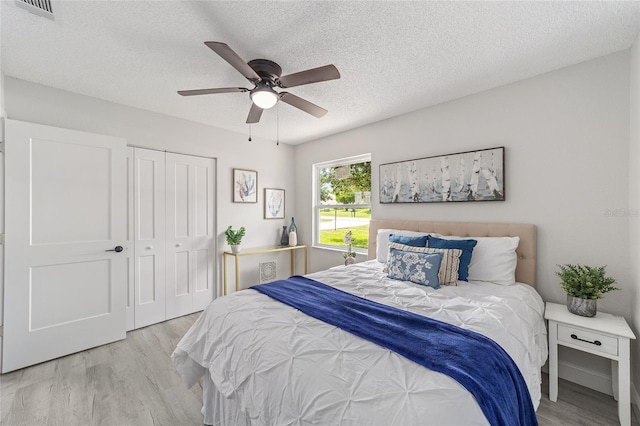 bedroom featuring a textured ceiling, ceiling fan, a closet, and wood finished floors