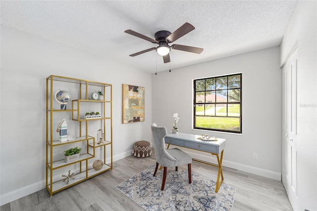 office featuring a ceiling fan, a textured ceiling, baseboards, and wood finished floors