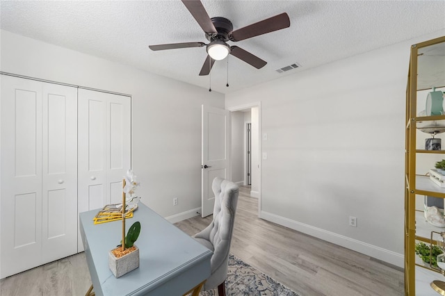 office space with baseboards, visible vents, ceiling fan, a textured ceiling, and light wood-style floors