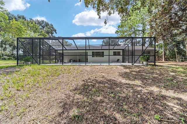 rear view of property featuring glass enclosure and an outdoor pool