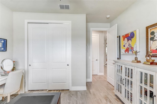 office space featuring light wood finished floors, visible vents, and baseboards