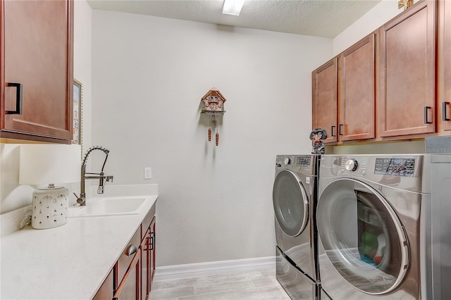 washroom featuring a textured ceiling, separate washer and dryer, a sink, and cabinet space