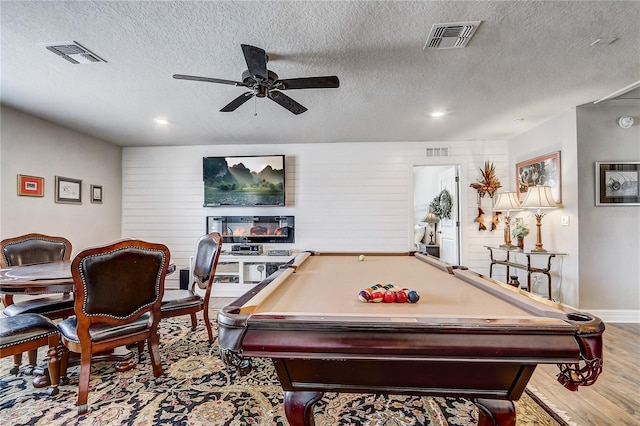 game room with light wood-style floors, ceiling fan, visible vents, and a textured ceiling