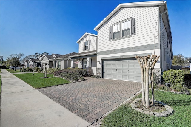 view of front of property with an attached garage, a residential view, decorative driveway, and a front yard