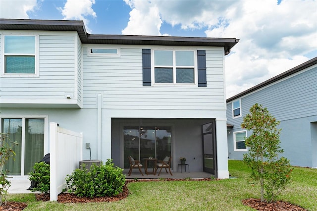 rear view of property featuring a sunroom, a lawn, and stucco siding