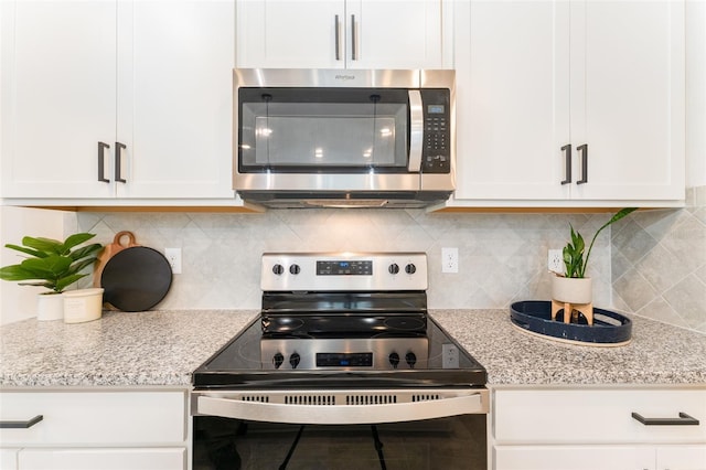 kitchen featuring tasteful backsplash, range with electric cooktop, stainless steel microwave, and white cabinets