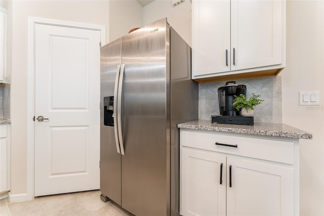 kitchen featuring white cabinetry, stainless steel fridge, light stone counters, and tasteful backsplash