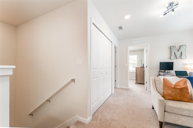 interior space with visible vents, baseboards, an upstairs landing, and light colored carpet