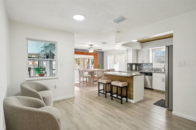 kitchen with a kitchen island, visible vents, white cabinets, appliances with stainless steel finishes, and a kitchen bar