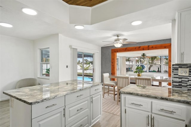 kitchen with recessed lighting, a ceiling fan, white cabinetry, light wood-type flooring, and light stone countertops