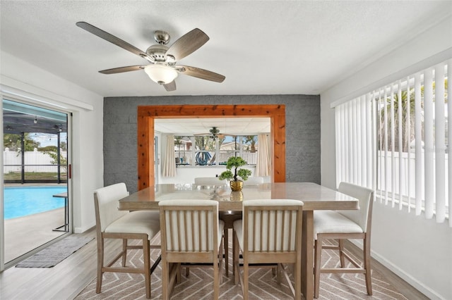 dining area with a textured ceiling, baseboards, and wood finished floors