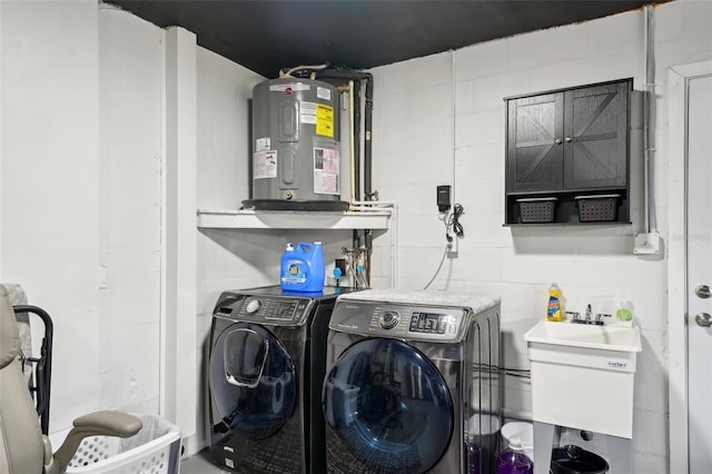 clothes washing area featuring concrete block wall, laundry area, washer and clothes dryer, electric water heater, and a sink