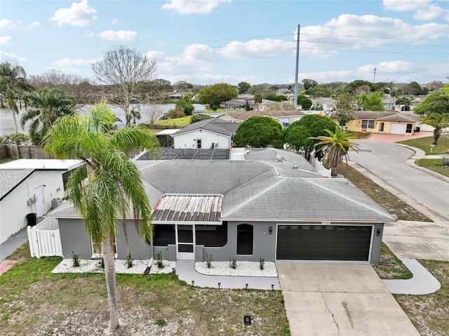 view of front facade featuring driveway, a shingled roof, a residential view, an attached garage, and stucco siding