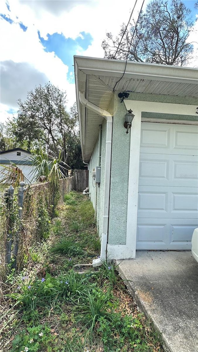 view of home's exterior featuring a garage, fence, and stucco siding